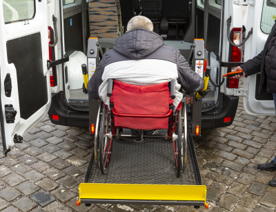 elderly man in wheelchair getting lifted to a van
