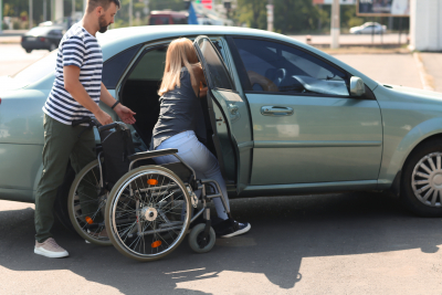 man assisting woman in wheelchair get in the car